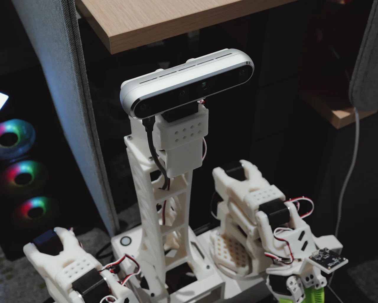 White robot with a stereo camera and two articulated grippers in a lab workspace
