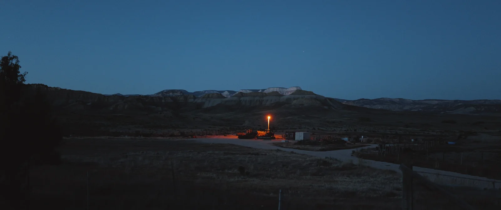 A solitary amber light beneath distant desert mesas in the blue evening light