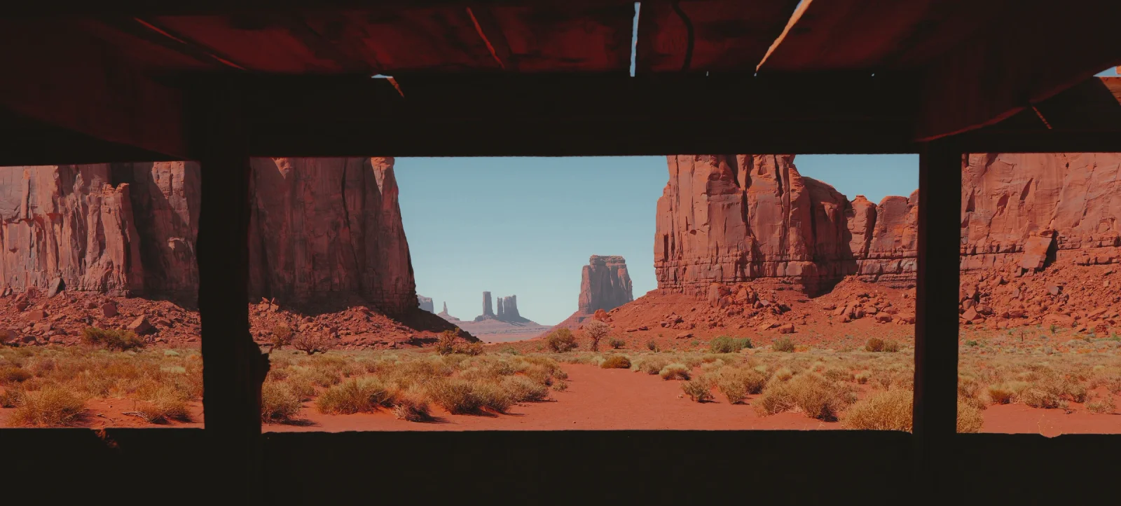 Red sandstone buttes framed by the dark wooden beams of a shelter